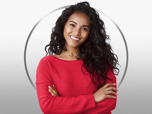 Young woman with dark hair wearing red sweater, standing confidently and smiling reassuringly